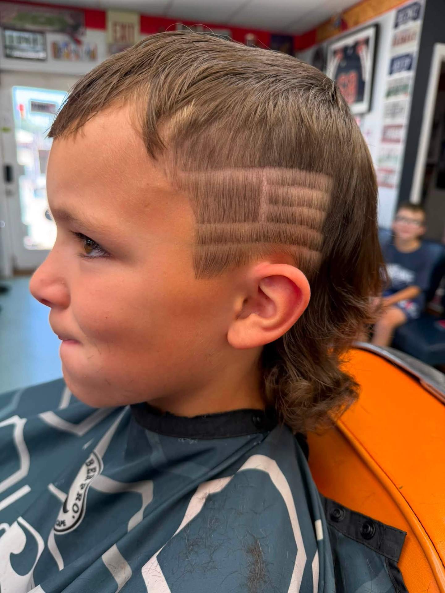 Kid showing a fresh creative haircut design in the chair